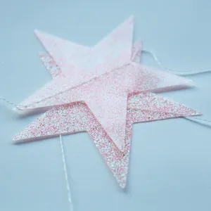 Gros plan d'une guirlande d'étoiles roses pailletées pour décoration de fête chic