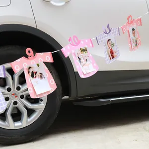 Baby monthly milestone photo banner featuring numbered cardstock hanging on a car