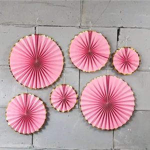 Detail of pink and gold foil paper fan set hung on a wall for festive party decoration