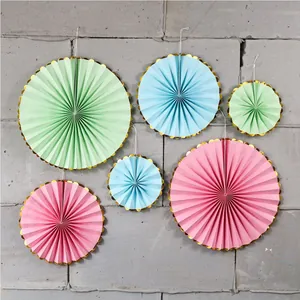 Close-up of pastel paper fans with gold wave edges for party wall decoration