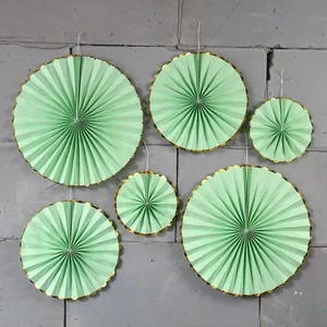 Close-up of 6-piece mint green paper fans with scalloped gold foil edges for party decor