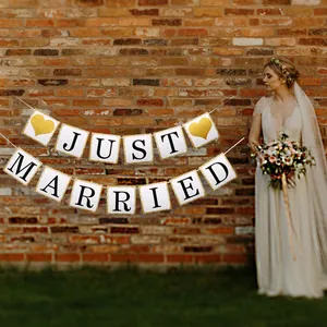 Close-up of Just Married banner with gold glitter edges and heart details on brick wall
