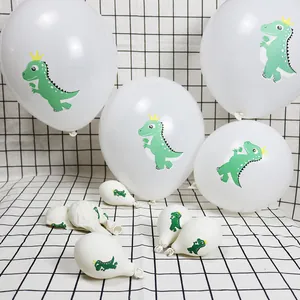 Détail de ballons en latex blancs avec de mignons imprimés de dinosaures verts et couronnes