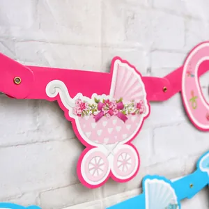 Dettaglio dello striscione in carta con carrozzina rosa e ciuccio per baby shower