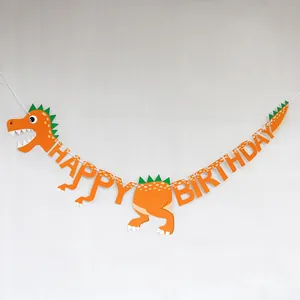 Detail of vibrant orange dinosaur birthday banner with green fins and happy birthday letters