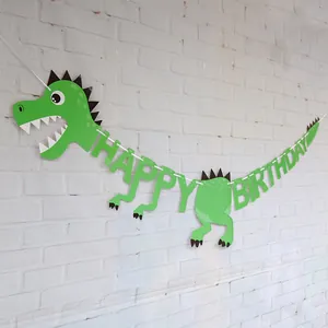 Green cartoon dinosaur Happy Birthday banner hanging on a white brick wall