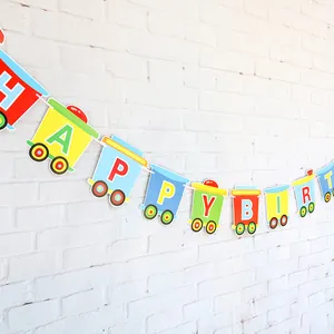 Colorful cartoon train bunting banner showing HAPPY BIRTHDAY letters on a white brick wall