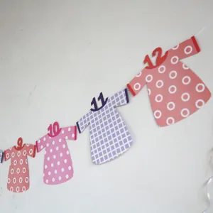 Detail of baby first birthday banner featuring colorful paper dress shapes and numbers