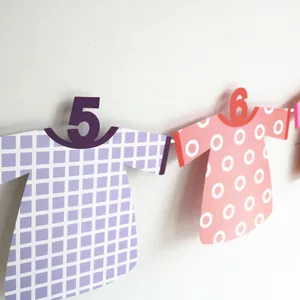 Detail of baby first birthday banner featuring t-shirt shaped paper cards with numbers