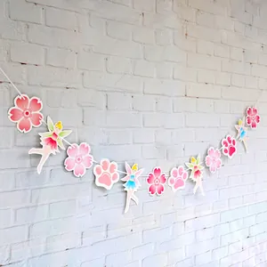 Dettaglio ghirlanda con fate e fiori di ciliegio su muro di mattoni bianchi