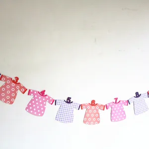 Detailed view of baby first birthday banner with colorful paper T-shirt garlands for party decor