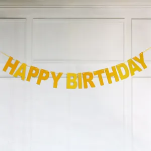 Glittery gold Happy Birthday paper banner with shimmering powder texture on white wall