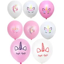 Detalle de globos de unicornio rosas y blancos con mantel festivo de rayas doradas