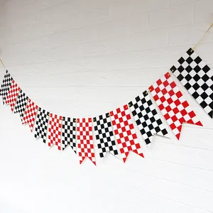 Racing checkered bunting flags in red and black hanging on a white brick wall