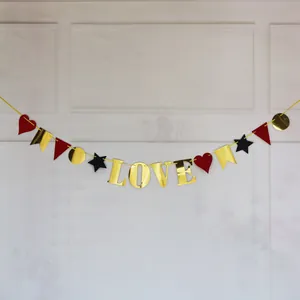Detail of gold LOVE letters banner with red heart and black star paper garlands