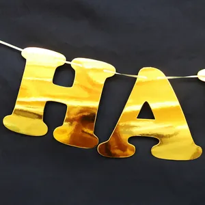 Close-up of shiny gold foil Happy New Year banner letters H and A with metallic finish