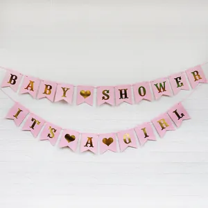 Baby Shower Girlande in Rosa mit goldener It's a Girl Aufschrift vor weißer Wand