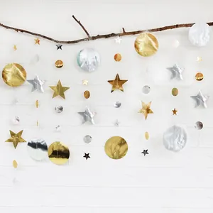 Detail of gold and silver star and circle garland hanging on a natural branch