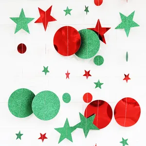 Close-up of red and green glittery star and circle garland hangings on white wall