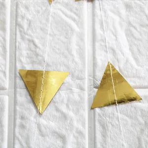 Close-up of golden mirror triangular banner flags with detailed white stitching for parties