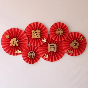 Detail of red wedding paper fans with gold glitter calligraphy and floral patterns