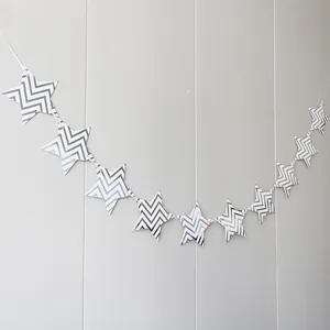 Detail of silver wavy star garland banner hanging on a white striped wall decoration