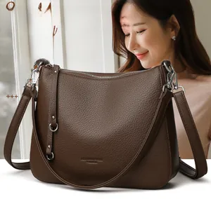Detailed view of dark brown litchi grain leather shoulder bag with silver hardware and zipper