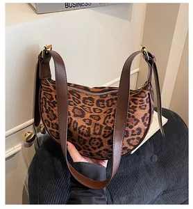 Detail of leopard print suede half-moon bag featuring brown leather strap and gold hardware