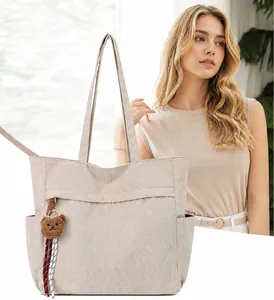 Dettaglio borsa tote in velluto a coste beige con ciondolo a forma di orsetto