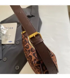 Detail of adjustable dark brown leather strap and gold buckle on leopard print bag
