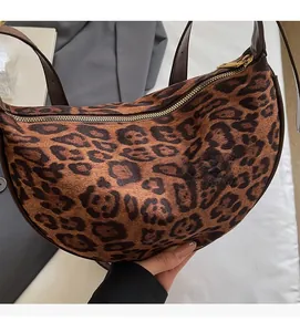 Detail of soft leopard print suede texture and gold zipper on crescent saddle bag