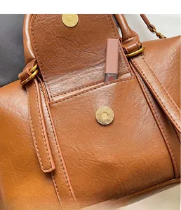 Close-up of golden hardware magnetic buckle and inner pocket on brown leather bag