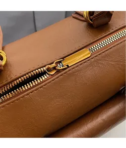 Macro detail of smooth golden hardware zipper pull on a brown leather handbag