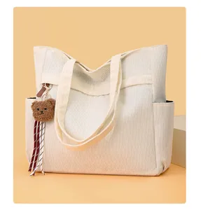 Dettaglio della borsa tote in velluto a coste bianco crema con ciondolo a orsetto