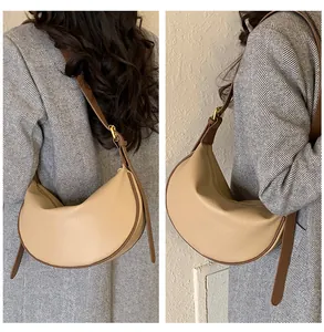 Detail view of beige crescent bag with brown leather trim and lychee grain texture