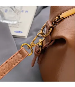 Detailed close-up of premium gold hardware hook on a vintage brown leather handbag