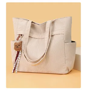 Dettaglio della borsa tote in velluto a coste beige con un ciondolo a forma di orsetto