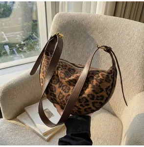 Detailed view of leopard print crescent bag featuring premium brown leather strap