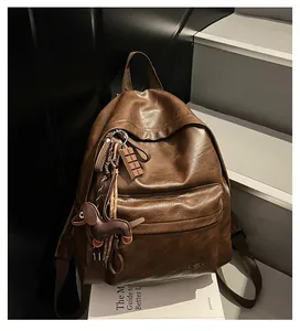 Détail du sac à dos vintage en cuir marron avec logo Hello et pendentif chien