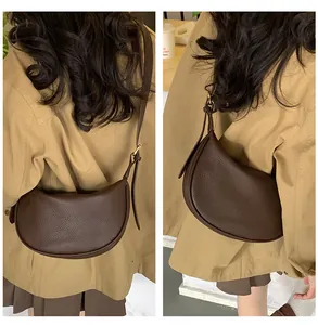 Detailed view of the dark brown pebbled leather texture on a stylish half-moon hobo bag