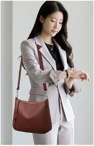Detail of burgundy lychee grain leather shoulder bag worn with a casual grey blazer