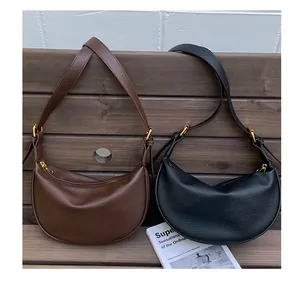 Detail view of dark brown and black textured leather crescent bags with gold hardware