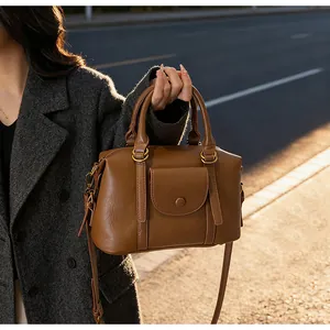 Detail of a brown leather handbag featuring a front pocket with gold-toned metal rings
