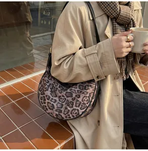 Detail of leopard print crescent shoulder bag on rustic steps with autumn outfit styling