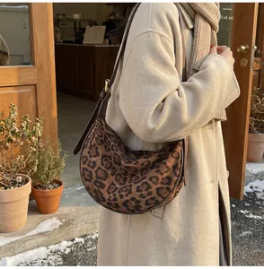Detail of leopard print crescent bag with leather strap shown in autumn setting