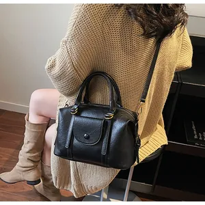 Fashionable black vintage boston bag worn as a crossbody with textured leather detail