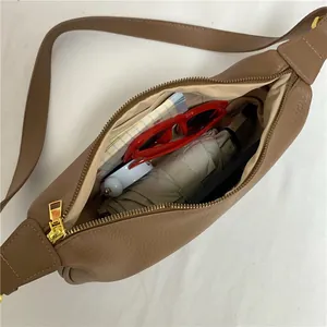 Brown leather dumpling bag with crossbody strap showing spacious internal storage capacity