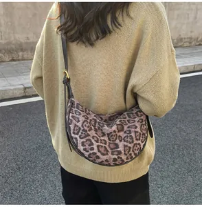 Outdoor shot of model wearing leopard print crossbody bag with black leather straps