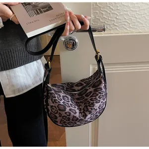Detail of leopard print crescent bag featuring gold hardware and adjustable strap