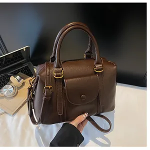 Detail of dark brown leather Boston bag with vintage gold hardware and flap pocket